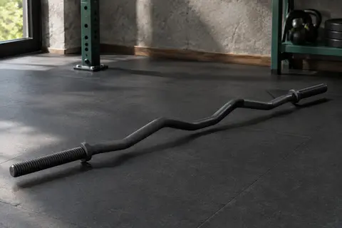 Barre de curl courbée noire avec moletage diamant et extrémités filetées dans un home gym