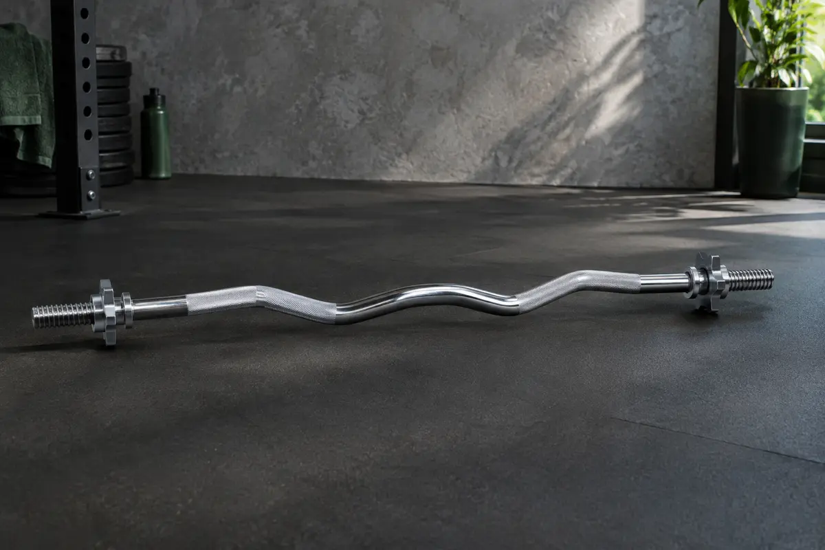 Barre curl chromée de 120 cm avec poignée antidérapante et fermetures à vis, dans un home gym.