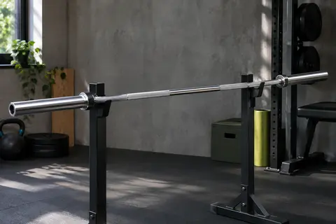 Barre olympique de 180 cm en acier, avec manchons de 50 mm et prise moletée dans un home gym.