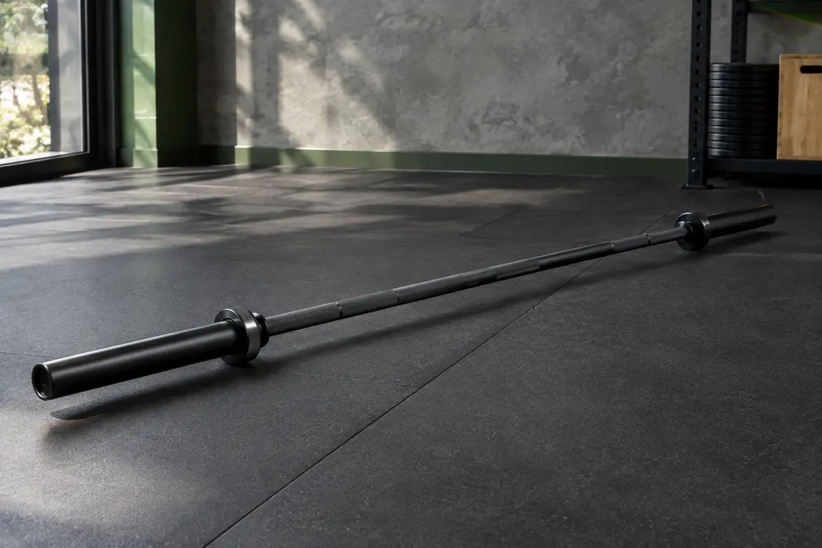 Barre olympique noire de 220 cm avec axe moleté et manchons de 50 mm dans un home gym