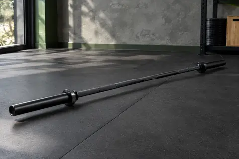 Barre olympique noire de 220 cm avec axe moleté et manchons de 50 mm dans un home gym