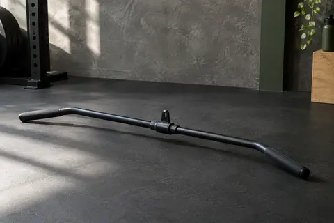 Barre droite rotative en acier avec poignée antidérapante, posée dans un home gym sobre et fonctionnel.
