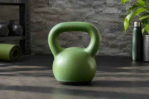 Kettlebell verte de 6 kg à poignée large, posée sur sa base plate dans un home gym
